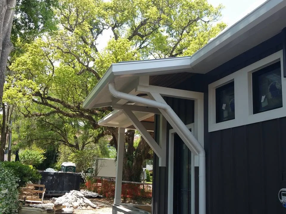 White downspout angled around porch bracket dark siding oaks, Sanford